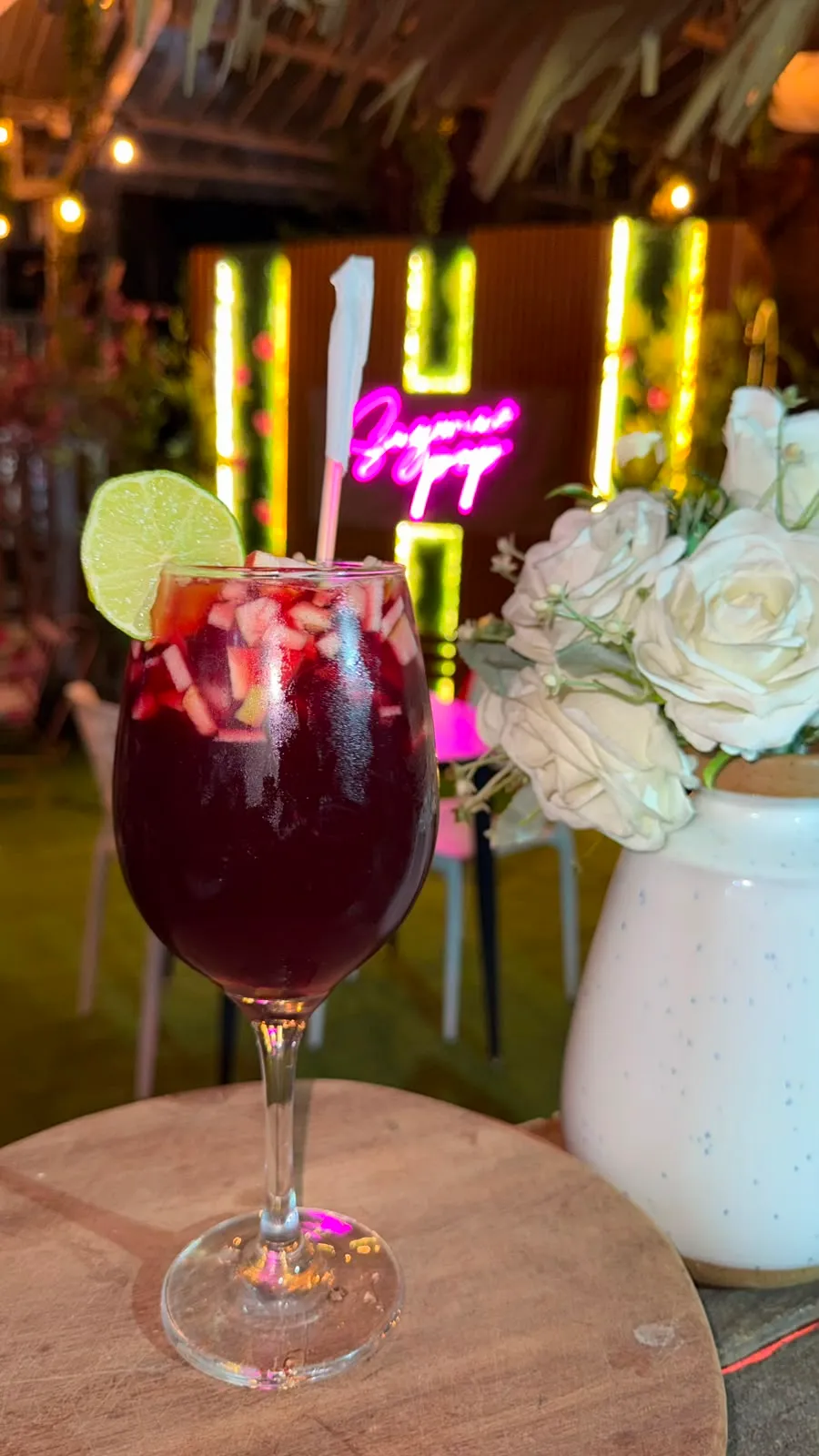 Copa de sangría con frutas junto a un ramo de rosas.