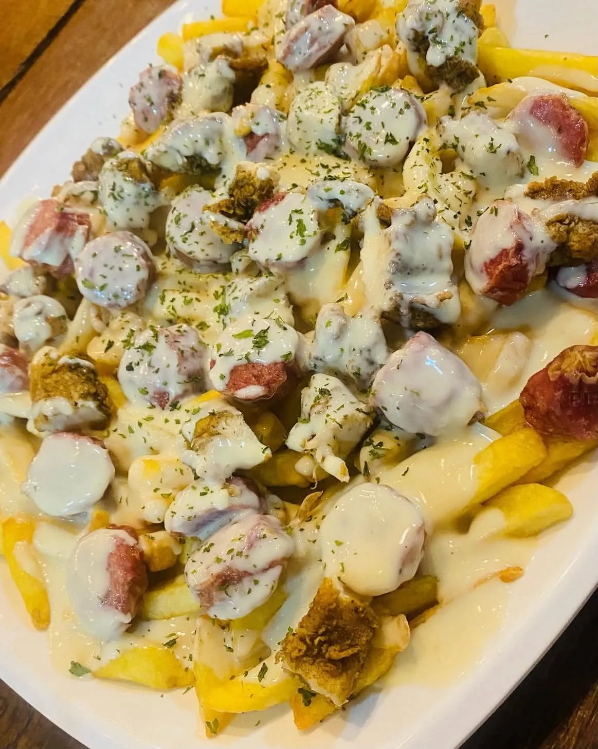 Papas fritas con salchicha y salsa de queso.