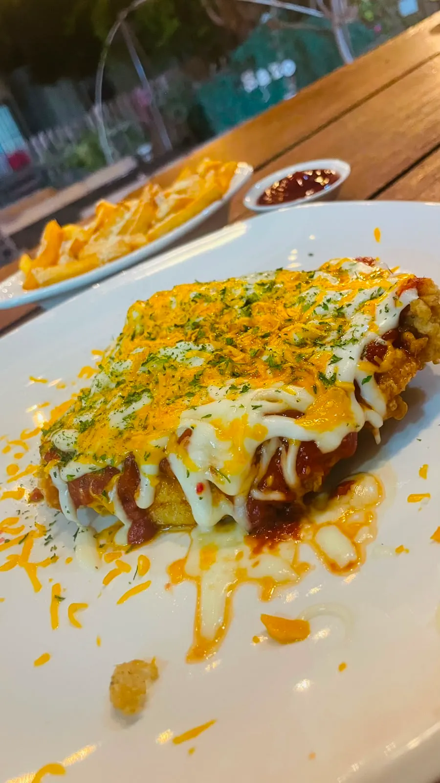 Milanesa dorada gratinada con quesos y hierbas, con papas fritas.